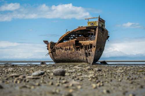 A Rusty Shipwreck Sits On the Shore Photo