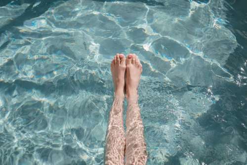 A Woman Points Her Toes While Stretching Her Legs In Pool Photo