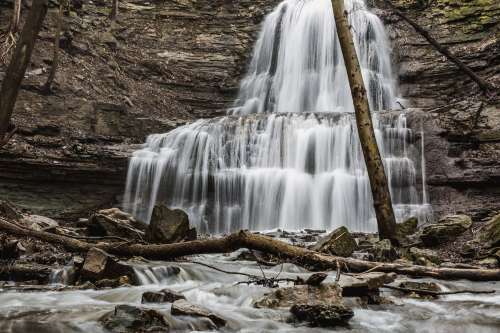 Cascading Waterfall Cuts Through Layers Of Rocky Cliffside Photo