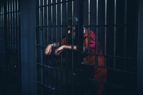 Crestfallen Prisoner Leans On Cell Door Photo