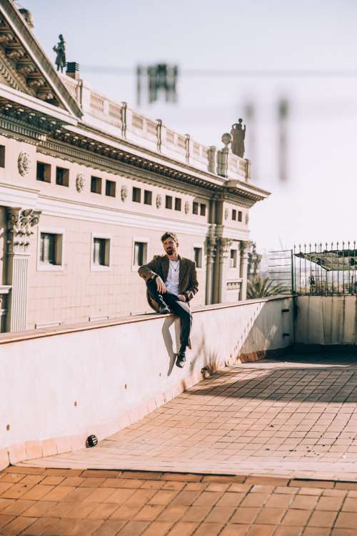Man Sits Casually On Roof Ledge Photo