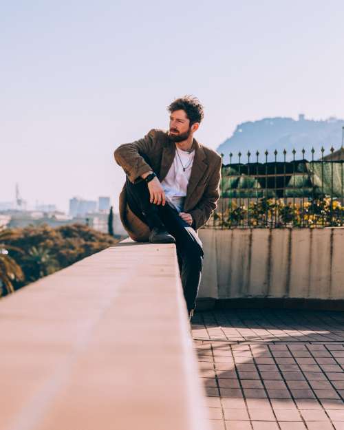 Man Sitting Comfortably On Roof Ledge Photo