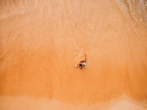One Man Lounges On The Beach At The Water's Edge Photo