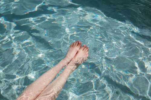 Womans Legs Stretched Into Pool With Baby Pink Toenails Photo
