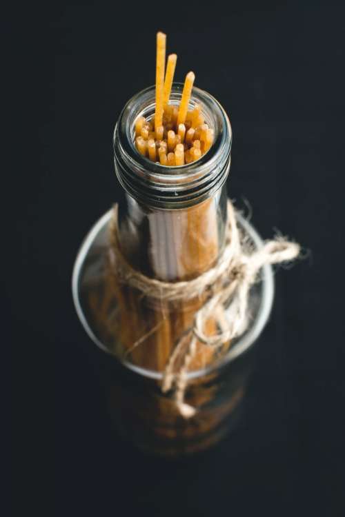 Spaghetti in an empty olive oil glass bottle