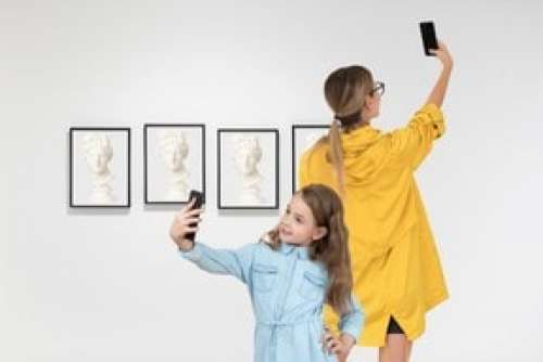 Mother And Daughter Making Selfies In Art Gallery