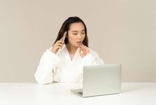 Young Asian Woman Talking On The Phone While Doing Online Shopping