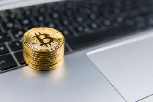 Golden Bitcoins on keyboard of metal laptop