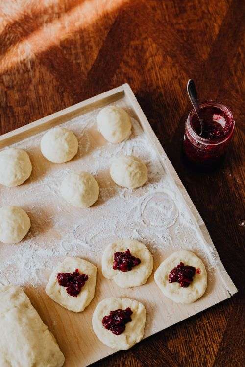 Adding cherry marmalade to Polish donuts - Paczki