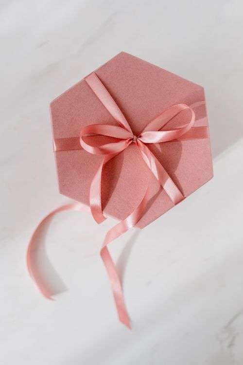Light pink velvety box with satin ribbon on white marble