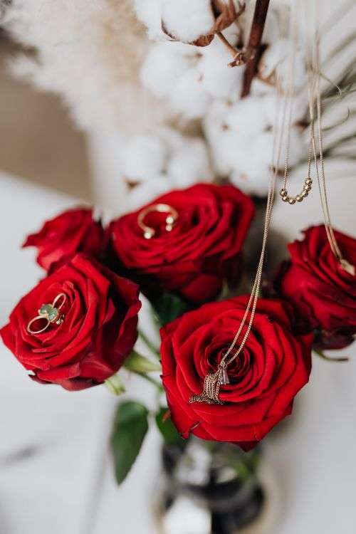 Red roses, gold jewellery and beauty accessories on white marble