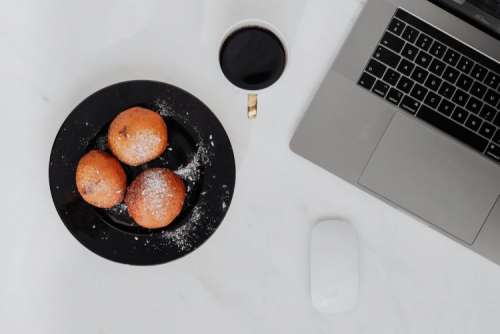 Marble desk with laptop, homemade Polish doughnuts and coffee