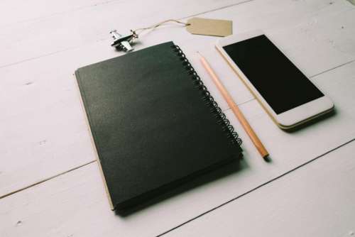 black notebook pencil mobile phone