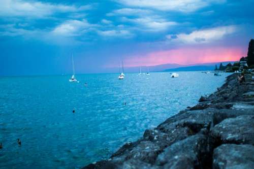 sunset sailboats lake water rocks