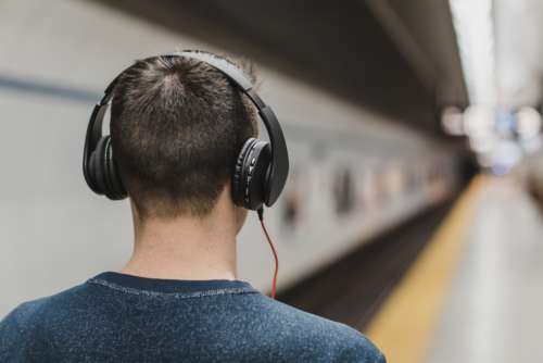 man walking train station headphones