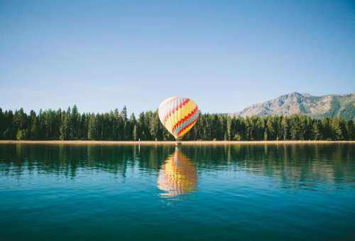 hot air balloon blue sky lake water