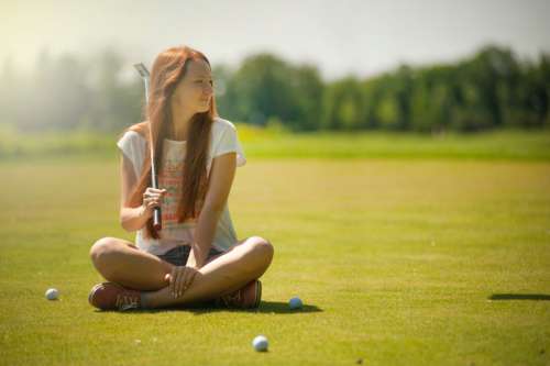 woman cross legged golf course sunny