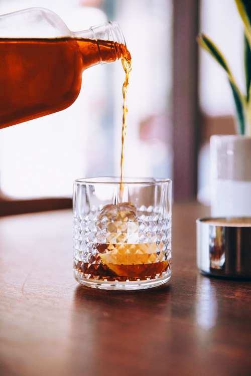 bourbon pouring glass on the rocks ice