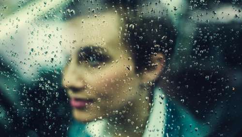 woman rain window wet bokeh