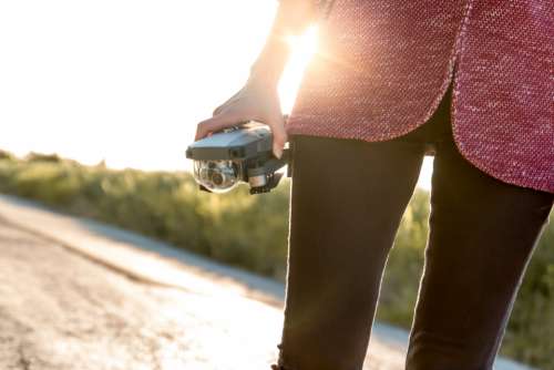 woman holding drone sunny road