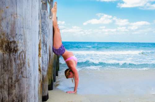 woman handstand beach ocean sea