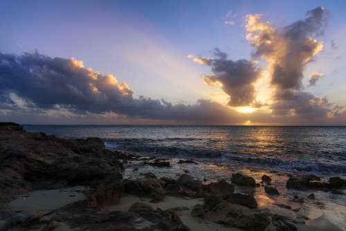 beach rocks sunset sky clouds