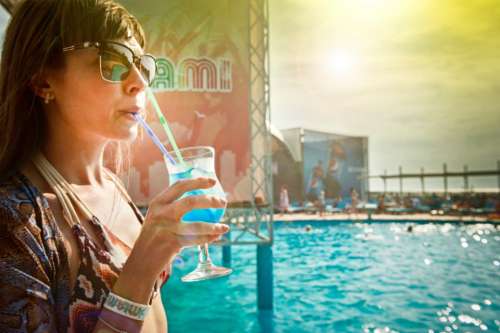woman drinking cocktail blue sunglasses