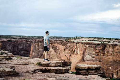 A Man On A Rocky Plateau Overlooks A Deep Canyon Photo