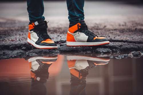 Bright Fashion Sneakers Reflect In Puddle On Asphalt Street Photo