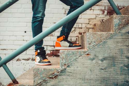 Model In Black And Orange Sneakers Perched Atop Stairs Photo