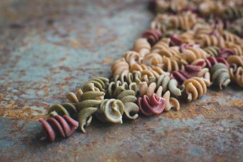 Colorful pasta fusilli on a rusty metallic background