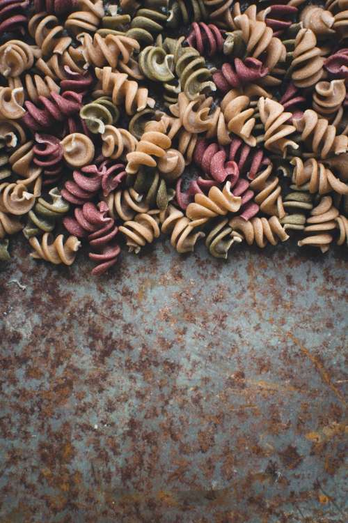 Colorful pasta fusilli on a rusty metallic background