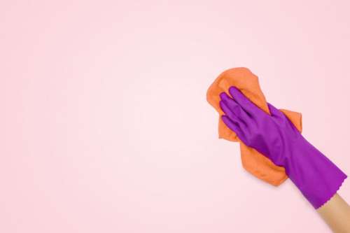 Employee hand in rubber protective glove with microfiber cloth wiping wall from dust