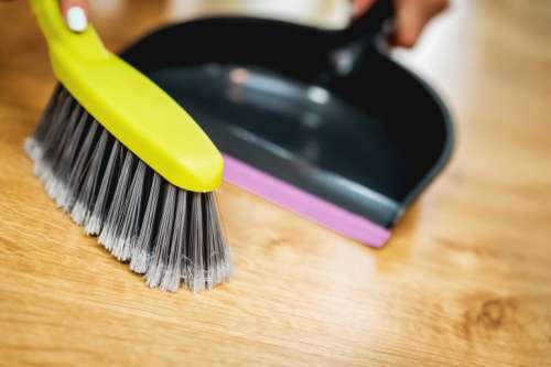 Green brush and dustpan on wooden background