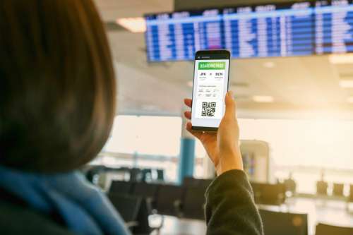 Woman looking at boarding pass on smart phone at airport