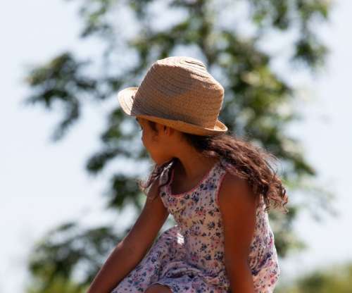 child in hat looking over left shoulder