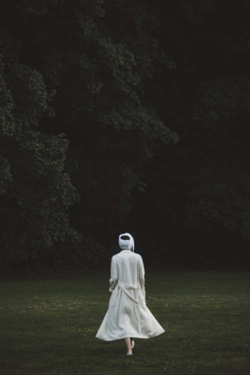 A Figure In White Gauze Walks Towards The Woods Photo
