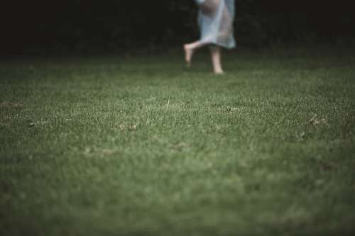 A Figure In White Netting Runs Across Lawn Photo
