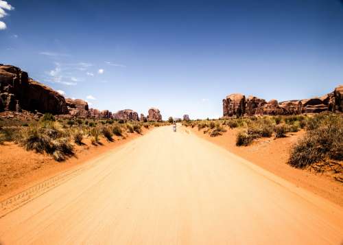 A Figure Stands On A Road In The Desert under Blue Skies Photo