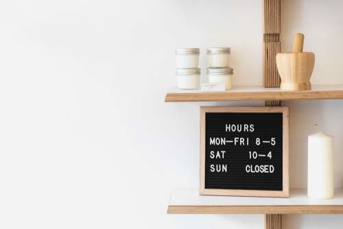 A Letterboard On A Busy Shop Shelf Denotes Opening Times Photo