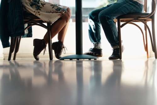A Man And A Woman's Feet Under A Table Photo