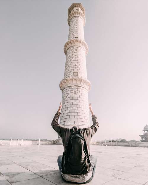 A Man Frames The Base Of A Tower With His Arms Photo