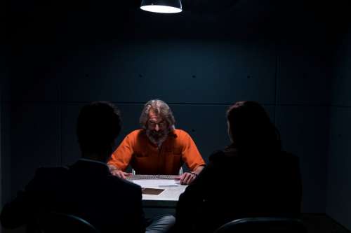 A Prisoner In An interrogation Room Glares At Detectives Photo