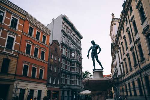A Statue Of A Man Holding A Ladle In A Town Square Photo