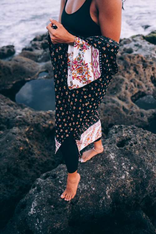 A Tanned Woman With Patterned Shawl Poses On Beach Photo