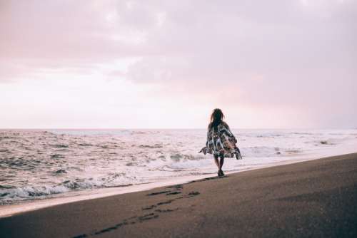 A Tanned Women In Flowing Beach Robe Walks Along the Beach Photo