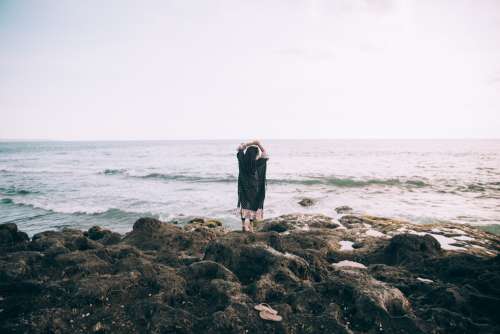 A Woman By The Beach Holds Her Hands Up In Reverie Photo