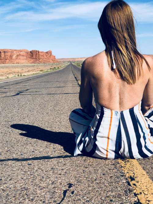 A Woman Sat In The Middle Of A Highway Through The Desert Photo