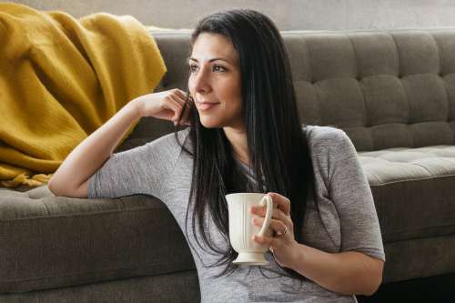 A Woman Sat With Coffee At The Foot Of A Sofa Photo