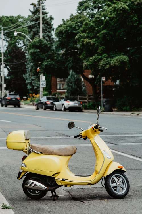 An Italian Summery Yellow Moped Parked On A Street Photo
